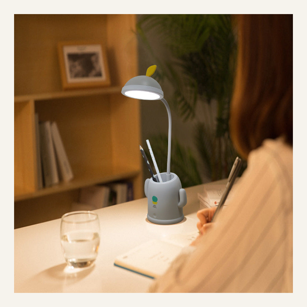 Green cactus desk lamp with pen holder in use at a desk