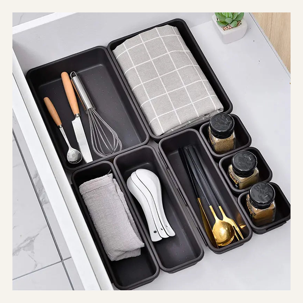 Gray interlocking drawer organizer bins holding kitchen utensils