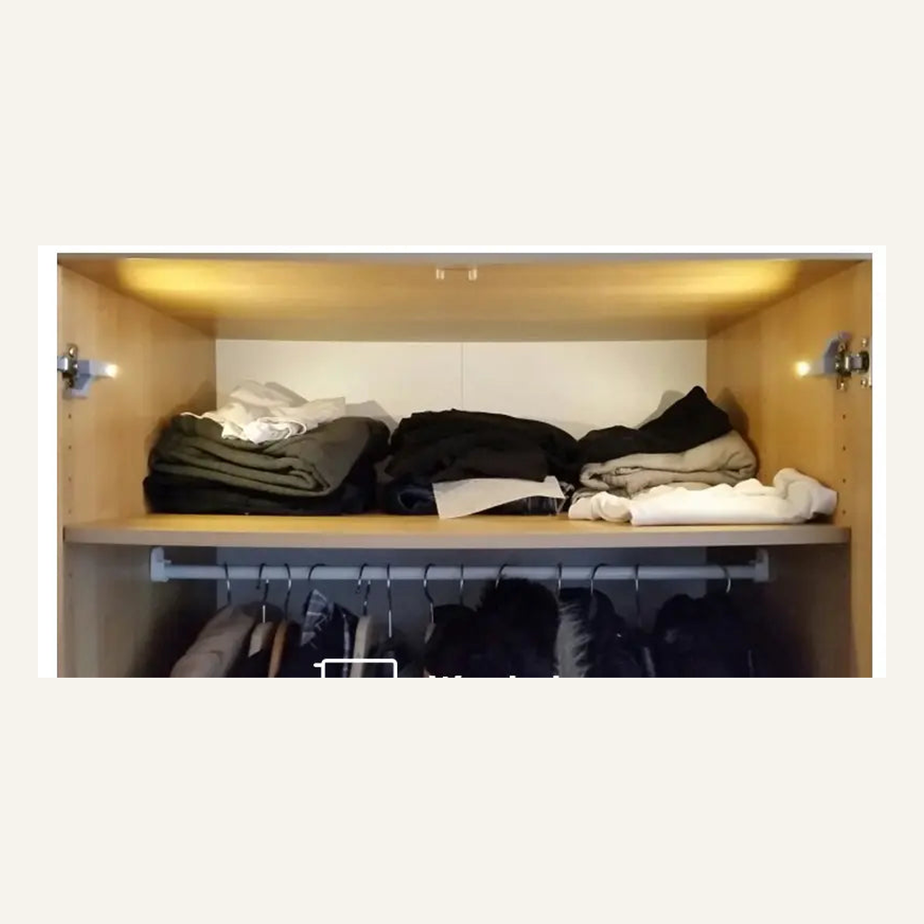 Cabinet hinge LED light illuminating a wardrobe