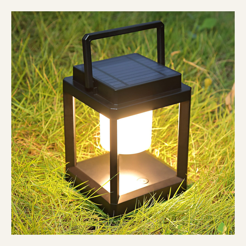 Black portable camping lantern illuminated on grass