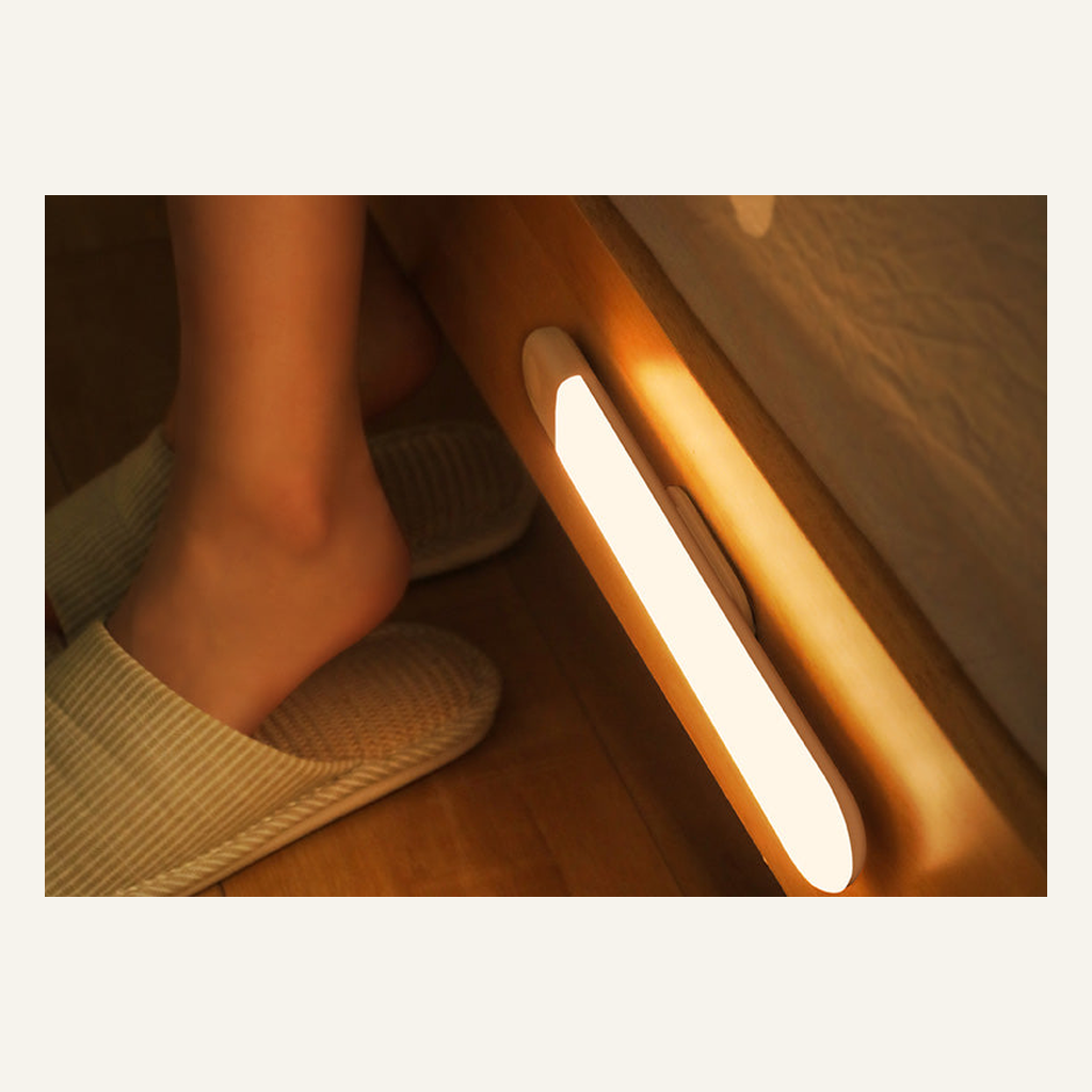 LED closet light bar illuminating the floor beside a bed